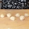 Chia bột làm bánh bao thành những phần nhỏ, vo tròn lại. Sau đó, ấn dẹp bột, cho hỗn hợp nhân trứng, bột bắp vào, vo lại.