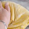 Cho bột mì, bột nở vào cùng, trộn đều và dùng tay nhào thật kĩ để bột được mềm, mịn.