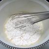 Trộn đều 200g bột mì, 1 muỗng canh bột nổi với 1/4 muỗng cà phê muối rồi rây vào hỗn hợp trứng, trộn đều. Sau đó, lọc hỗn hợp qua rây cho mịn.