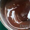 Đổ ít nước vào một cái nồi nhỏ, đun sôi. Cho chocolate và bơ vào âu sạch, đặt lên miệng nồi rồi khuấy cho hỗn hợp tan chảy. Nhấc âu ra khỏi nồi, cho đường và bột cacao vào khuấy đều (A).