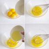 Đánh 4 lòng đỏ trứng với 20gr đường. Chia dầu bắp thành 3 phần, lần lượt cho vào lòng đỏ trứng. Cứ mỗi một lần cho vào lại đánh đều rồi mới đổ tiếp lượt dầu mới.