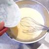 Đánh bong trứng gà với 50g đường trong tô lớn rồi cho 150ml nước, 15ml mật ong và 15ml dầu ăn vào trộn đều. Trộn đều bột mì với bột nở trong tô khác rồi nhẹ nhàng cho vào hỗn hợp trứng ở trên, trộn nhẹ nhàng thành hỗn hợp đồng nhất.