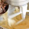 Cho trứng gà và tinh chất vani vào hỗn hợp trong máy đánh bột, tiếp tục đánh ở tốc độ vừa cho nhuyễn mịn trong 20-30 giây. Cho tô hỗn hợp bột mì vào đánh thêm 20-40 giây nữa. Cuối cùng là chocolate chips và dừa nạo, bạn cho vào đánh cho hòa quyện.