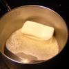 Cho bơ vào nồi, nấu tan chảy. Sau đó, cho bơ, vỏ cam vào hỗn hợp ở bước 1, trộn đều.