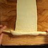 Cách làm bánh mì cua (cách tạo hình) đẹp mắt: Díu các mép bột làm bánh mì cua phô mai lại để có phần bột hình viên tròn với mặt bột căng, sau đó vo dài viên bột khoảng 30cm với một đầu to và đầu còn lại nhỏ hơn. Dùng cây cán bột cán mỏng bột bánh mì sau đó tạo hình 2 càng cua, cho miếng phô mai ở giữa và bắt đầu cuộn lại để tạo thành hình con cua hoàn chỉnh. Không nên cán quá mỏng vì bánh mì cua nhân phô mai sau khi nướng sẽ dễ bị mất các dấu vân.