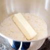 Sau đó, cho 25g bơ vào, dùng máy trộn điện trộn cho đến khi hỗn hợp hòa quyện với nhau, khoảng 3 phút.