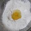 Hành lá rửa sạch, cắt nhỏ. Cho bột mì, trứng gà, hạt nêm, muối và khoảng 1/2 chén nước lọc vào tô lớn, trộn đều thành một khối bột đồng nhất.