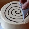 Cho chocolate vào túi bóp kem rồi vẽ thành hình vòng tròn trên mặt bánh.