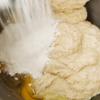 Để hoàn tất phần bột, bạn cho nốt phần bột mì còn lại và 1 quả trứng vào rồi đánh đều tất cả lên cho đến khi được hỗn hợp mịn và hơi dính. Cho bột ra tô, bọc nylon thực phẩm rồi để cho bột nở trong khoảng 2 tiếng.
