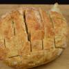 Dùng dao rạch ổ bánh mì tròn thành các khối vuông nhỏ có kích cỡ 2.5 cm nhưng không đứt rời ra (vỏ phía dưới bánh mì vẫn còn nguyên).
