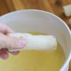 Cuộn bánh mì lại, nên cuộn chặt tay để nhân không bị rơi ra. Đánh trứng và sữa trong 1 cái bát to rồi nhúng cuộn bánh mì vào.