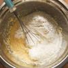 Sau đó cho 120ml nước cốt dừa vào, vẫn tiếp tục dùng máy đánh trứng trộn hỗn hợp ở tốc độ vừa. Cho bột mì, baking powder, baking soda, cơm dừa nạo vào một tô khác trộn đều lên. Sau đó đổ vào hỗn hợp bơ trứng ở bước trên, trộn đều. Cắt mít thành từng sợi nhỏ, cho vào tô bột, trộn đều lên.