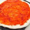 Dùng thìa phết đều một lớp sốt vừa trộn lên đế bánh pizza. Rắc một lớp phô mai bào nhỏ lên trên sốt.