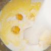 Đun sữa tươi ở lửa nhỏ cho đến khi sữa âm ấm thì tắt bếp. Sau đó, cho men nở vào. Tiếp đến, cho trứng, 15g bơ lạt, 55g đường trắng, muối và 2 muỗng cà phê vani vào.