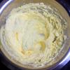 Dùng kéo cắt chuối sấy thành những miếng nhỏ. Làm mềm bơ ở nhiệt độ phòng, cho bơ vào thố dùng máy đánh trứng đánh ở tốc độ chậm, sau đó thêm đường từ từ vào, đánh cho đến khi bơ chuyển màu vàng nhạt.