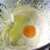 Cho bơ vào âu, đánh bông. Cho đường vào đánh với bơ. Khi bơ chuyển màu sáng thì dừng lại, bật lò nướng ở 200 độ C. Đập trứng vào âu.