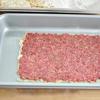 Tiếp theo, cắt mì thành những miếng vuông góc, rắc bột lên trên rồi trải đều thịt bò lên mì. Sau đó, đặt thêm 1 lát mì lên thịt, ấn nhẹ, rắc thêm bột mì.