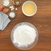 Cho vào tô lớn 270gr bột gạo, 30gr bột nếp, 30gr bột năng và 1 muỗng cà phê bột vani. Cho nước trứng gà lọc qua rây vào hỗn hợp bột, dùng phới dẹt trộn đều.