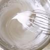 Chia 20g đường làm 3 phần. Cứ mỗi lần cho 1 phần đường vào thố lòng trắng trứng thì dùng máy đánh trứng đánh bông lên. Đến lần cuối cùng, đánh bông lòng trắng trứng thành hỗn hợp kem, bám hình chóp trên que đánh trứng.