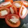 Rửa sạch cà chua, bổ đôi, cho vào chảo cá đang kho. Nấu cho cà chua chín. Hành lá cắt khúc tầm 2cm, cho vào chảo cá.