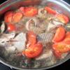 Khi cà chua sôi lên, trút cá đã ướp vào nồi. Tiếp tục nấu cho nồi cá sôi trở lại, vớt bọt, nêm nếm lại sao cho cá có vị vừa ăn. Tắt bếp rắc thêm tiêu, hành lá, ngò rí.
