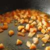 Tiếp theo, cho 1/2 muỗng canh dầu vào chảo sâu lòng, cho cà chua cắt hạt lựu vào, xào đều một lúc. 