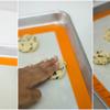 Lót một tấm nhựa chịu nhiệt chuyên dùng cho nướng bánh (hoặc có thể lót giấy nến). Lấy muỗng múc kem hay muỗng tròn, múc 1 muỗng bột cho lên khay nướng, dùng tay ấn dẹp viên bột cookie xuống. Giữ khoảng cách giữa các bánh cookie để tạo không gian cho bánh nở ra. Bật lò trước đó khoảng 10 phút ở 200 độ C. Đặt khay bánh cookie vào lò và nướng từ 12 - 15 phút đến khi bánh chín, có màu vàng nâu, giòn tan thì tắt lò. Lấy bánh ra để nguội rồi cho vào hũ thủy tinh bảo quản và dùng dần.