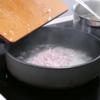 Trong một cái chảo sâu lòng hoặc nồi nấu cơm, bật lửa vừa, cho chút dầu vào chảo. Cho hành vào phi thơm. Thêm gạo vào chảo và lắc đều. Thêm nước dùng gà và nước vừa luộc cánh gà vào chảo.