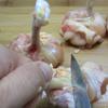 Rửa sạch đùi gà, dùng dao cắt gân xung quanh xương rồi đẩy thịt và da gà về phía đầu xương.