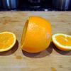 Đầu tiên, ta cắt rời 2 phần chóp của trái cam ra. Chú ý là cắt một phần chóp mỏng và một phần thì dày hơn một chút nhé!