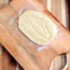 Cách làm kem chuối: Dùng dao rạch 1 bên túi nylon, tiếp theo cho trái chuối vào và dùng vật nặng ấn dẹp trái chuối.