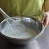 Chuẩn bị nguyên liệu và dụng cụ cần cho món kem. Trong 1 tô trộn, cho 2 hũ sữa chua, 50g đường, 50ml nước vào khuấy đều.