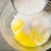 Tách trứng gà chỉ lấy lòng đỏ. Cho lòng đỏ trứng gà cho vào tô, đánh tan sau đó từ từ đổ 1 lượng nhỏ kem nóng ở trên vào trộn đều lên.