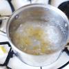 Cho nước vào một cái nồi bắc lên bếp, đợi sôi luộc nui nơ. Sau đó vớt ra dội nước lạnh để nui dai và không bị dính vào nhau.