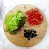 Gọt vỏ xoài chín, cắt hạt lựu. Cắt nhỏ rau salad, bổ đôi cà chua bi và cắt khoanh olive đen.