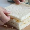Dùng dao cắt bỏ rìa bánh sandwich, phết hỗn hợp trứng mayonnaise lên lát sandwich, sau đó kẹp một lát bánh, tiếp tục phết trứng mayo vào lát bánh. Cuối cùng đặt 1 lát sandwich, tạo thành 3 lớp sandwich và 2 lớp nhân.