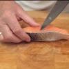 Cắt miếng fillet cá hồi thành từng lát mỏng dày 0.5cm. Lưu ý không cắt rời hẳn mà đế lớp da dính lại. 