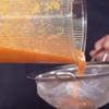 Khi hỗn hợp sinh tố cam được xay nhuyễn thì lọc tiếp sinh tố qua rây để chúng được mịn rồi đổ sang một ly thủy tinh sạch nhé! Thêm đá viên nhỏ vào gần đầy ly. Lấy thìa, gạn phần ruột chanh dây rồi nhẹ nhàng đặt lên trên để trang trí. Cuối cùng là thêm nước chanh vào để tạo thêm vị chua và hương thơm.