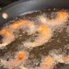 Làm nóng dầu ăn trong chảo, cho tôm vào, chiên vàng giòn. Sau đó, vớt tôm ra đĩa, để ráo dầu.