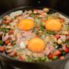 Tiếp đó đập 4 quả trứng gà vào chảo rau củ, dùng đũa hay mui làm trứng bể ra rồi đảo đều cho trứng phủ đều khắp chảo. Rắc phô mai Parmesan lên và đậy nắp lại khoảng 1 - 2 phút là có thể tắt bếp được rồi đó.