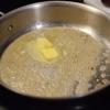 Sau đó, cho 10g bơ vào chảo. Bật bếp nhiệt độ trung bình. Phi thơm 2 tép tỏi đập dập. 